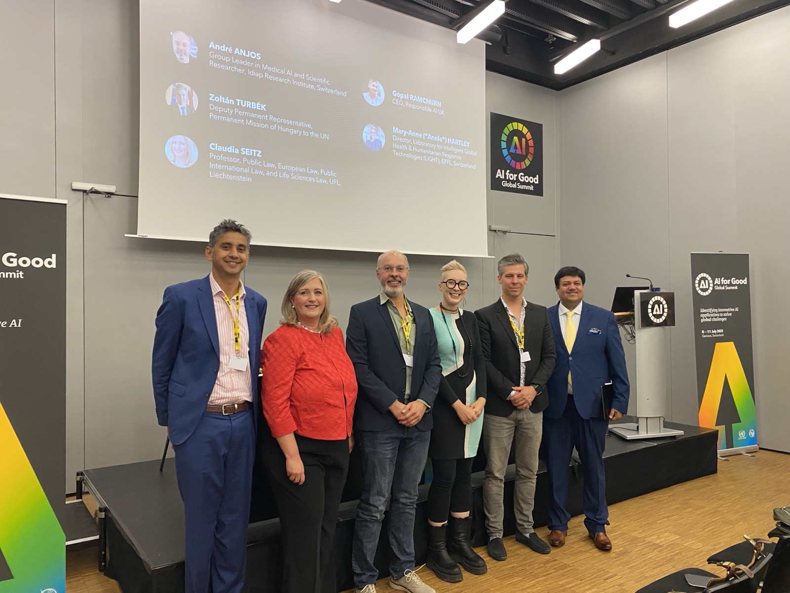 The panel speakers gathered in front of the stage, with the speaker slide projected behind