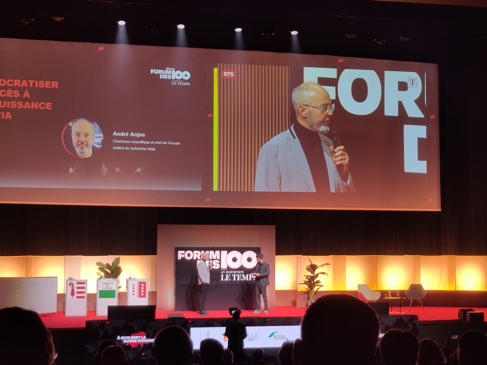 André Anjos on stage at the Forum des 100, projected on the screen above